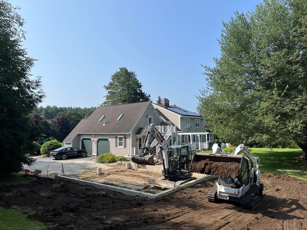 Excavation equipment on a residential property, preparing the ground for construction.